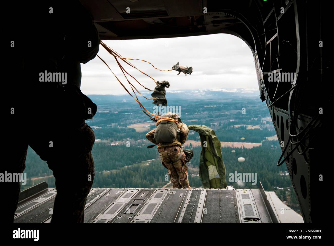 Soldats de la Garde nationale de Washington avec 1st Bataillon, 168th General support Aviation Regiment (GSAB), 96th Aviation militaire Command, transport 1st Special Forces Group (Airborne) et des partenaires canadiens au-dessus de la zone de dépôt Rogers sur la base interarmées Lewis-McChord, Washington, 6 décembre 2022. Le saut de ligne statique conjoint faisait partie des célébrations annuelles de la semaine de Menton 78th commémorant l'anniversaire de la désactivation combinée de la première force de service spéciale des États-Unis et du Canada. (É.-U. Photo de la Garde nationale de l'armée par le sergent d'état-major Adeline Witherspoon) Banque D'Images