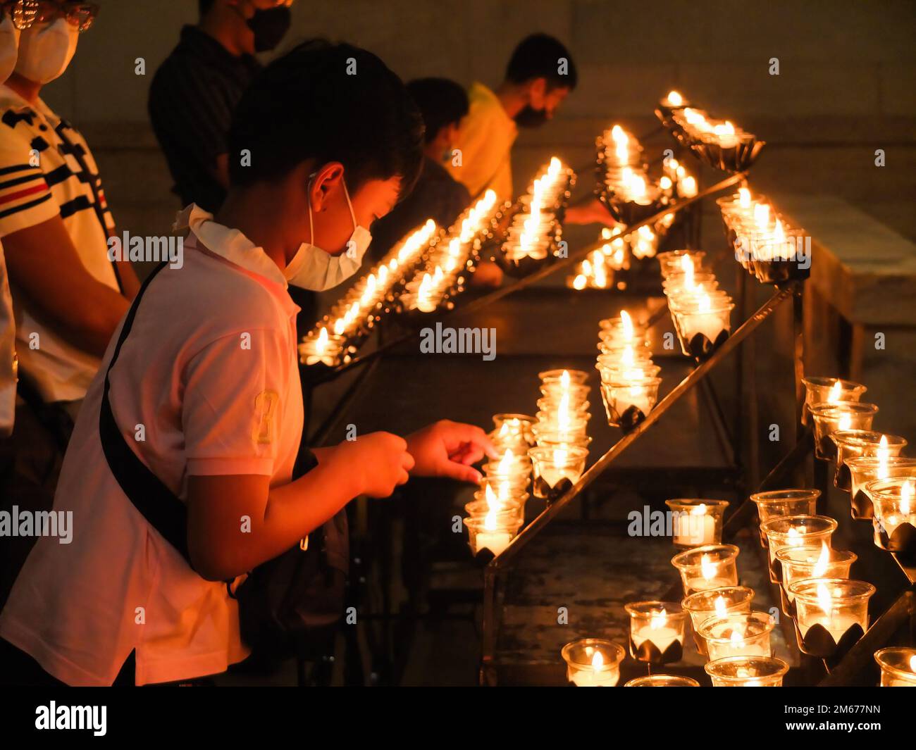 Manille, Philippines. 02nd janvier 2023. Un jeune garçon allume une bougie pour donner son dernier respect au regretté Pape émérite Benoît XVI Les dévotés catholiques accordent leur dernier respect au Pape émérite Benoît XVI en offrant des prières, en éclairant des bougies et en écrivant le livre de condoléances pour le souverain pontife tardif à la Chapelle Christ Roi de la Cathédrale de Manille, lundi, 2 janvier. Le pape tardif dont le nom de naissance était Joseph Aloisius Ratzinger est mort à l'âge de 95 ans dernier 31 décembre 2022 au monastère de Mater Ecclesiae dans la Cité du Vatican. Crédit : SOPA Images Limited/Alamy Live News Banque D'Images