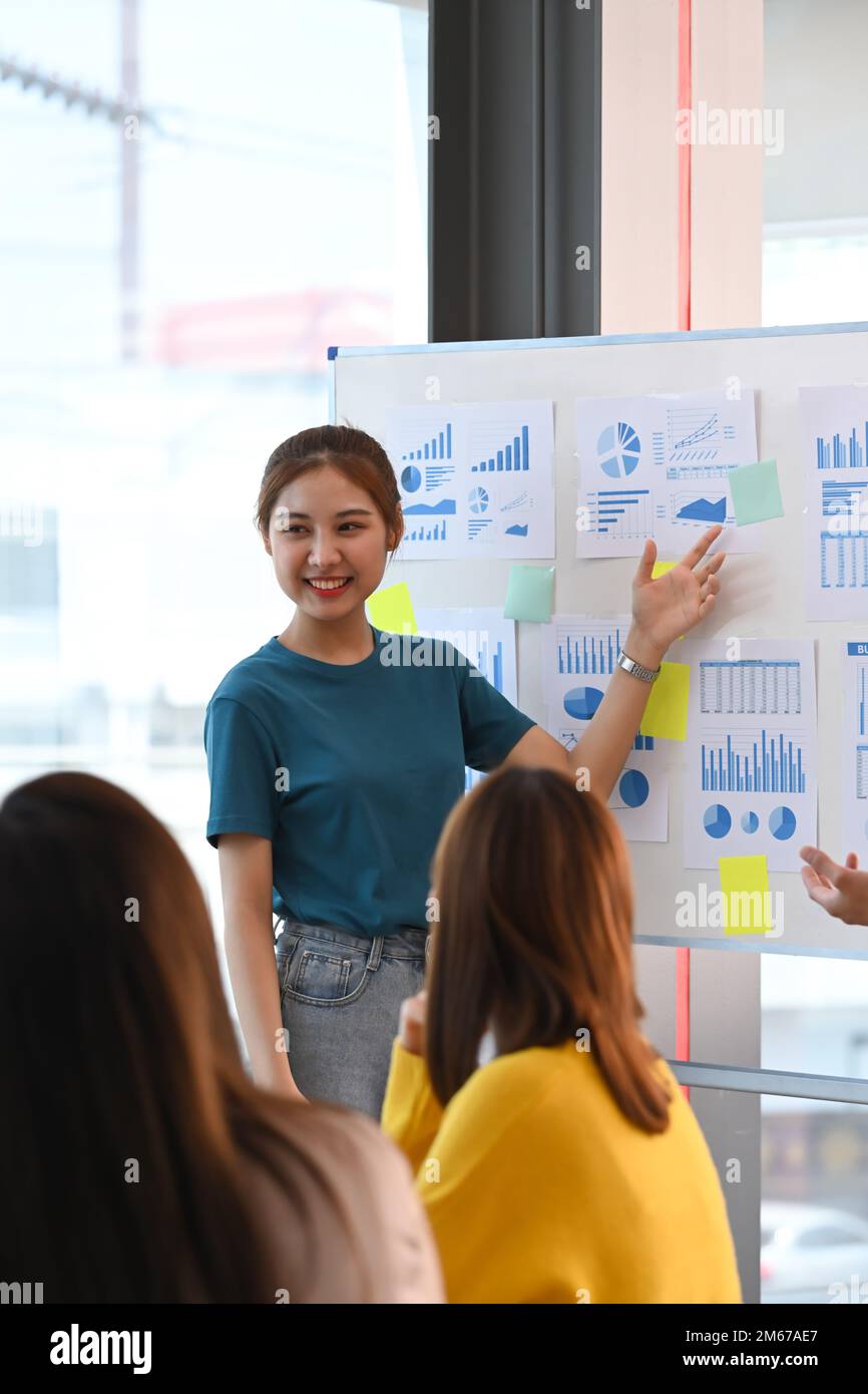 Jeune femme confiante partageant des idées stratégie d'affaires, expliquant de nouvelles stratégies sur tableau blanc à ses collègues Banque D'Images