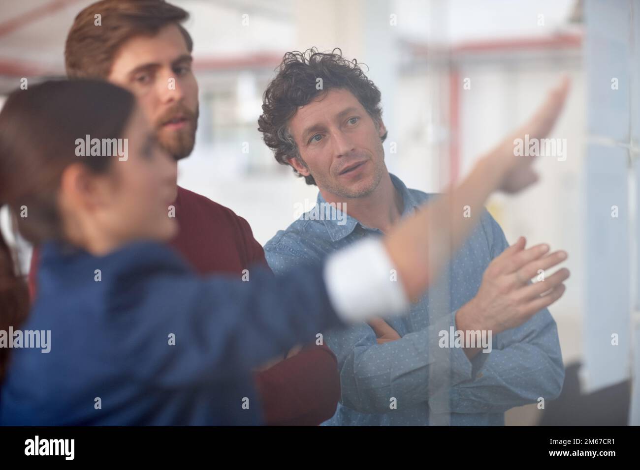 Collaborer sur un projet créatif. Un groupe de professionnels de la création travaillant ensemble sur un mur de verre avec des dessins. Banque D'Images