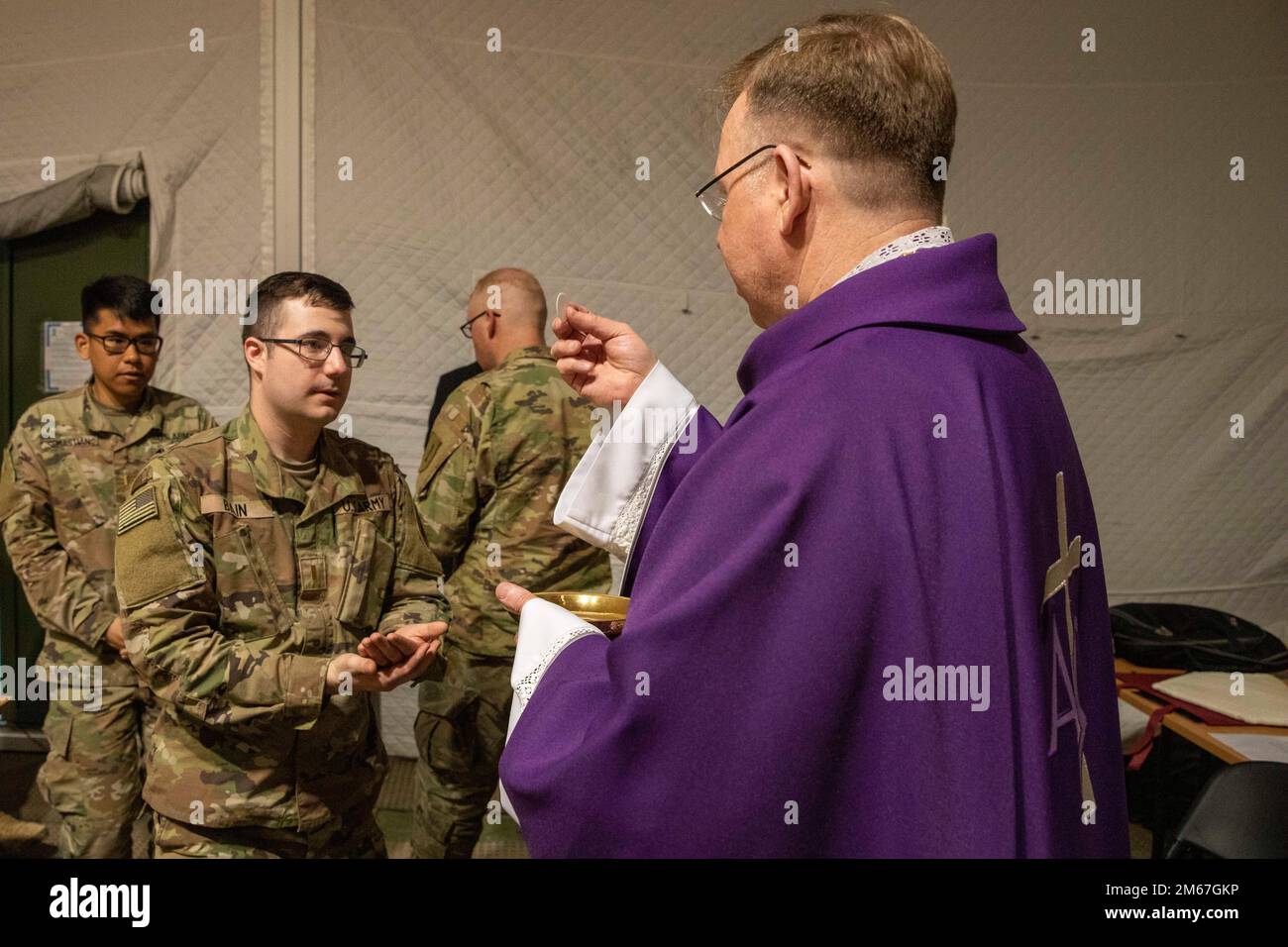 L'archevêque lituanien Gintaras Grušas présente le 2nd Lt. Ian bain, officier blindés du 3rd Battalion, 66th Armored Regiment, 1st Armored Brigade combat Team, 1st Infantry Division, avec la Sainte communion lors d'une messe catholique au Camp Herkus, Lituanie, le 12 avril 2022. Résolution atlantique, lutte comme un, les gens d'abord, plus fort ensemble, armée américaine, Banque D'Images