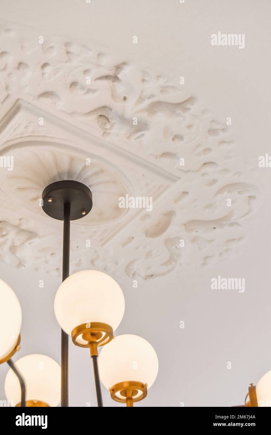 une chandel accrochée au plafond dans une pièce avec du papier peint blanc et une bordure dorée autour de la lumière Banque D'Images