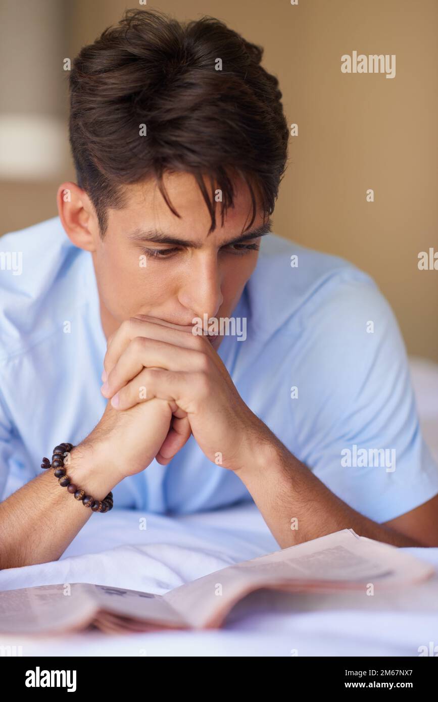 Mise à jour. un beau jeune homme lisant un journal dans sa chambre. Banque D'Images