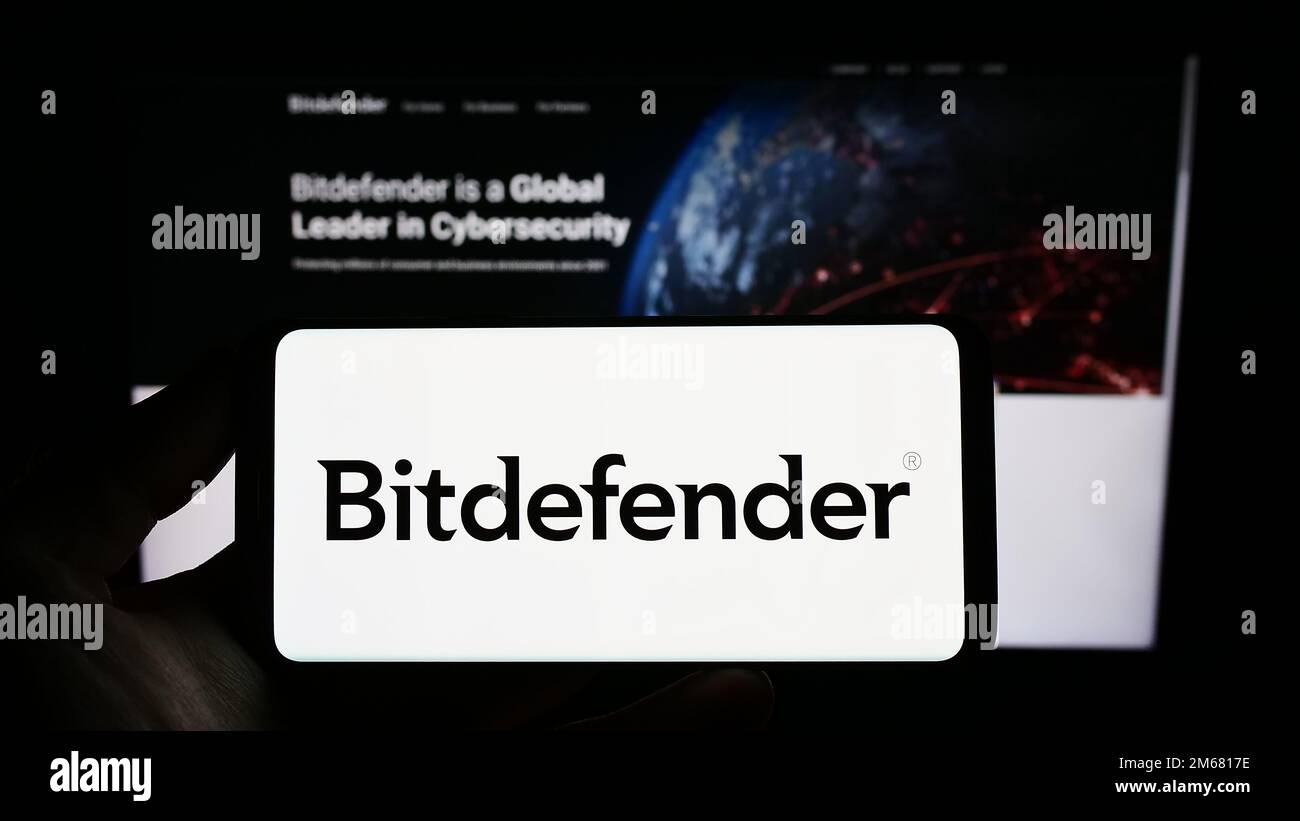 Personne tenant un smartphone avec le logo de la société roumaine de cybersécurité Bitdefender à l'écran devant le site Web. Mise au point sur l'affichage du téléphone. Banque D'Images