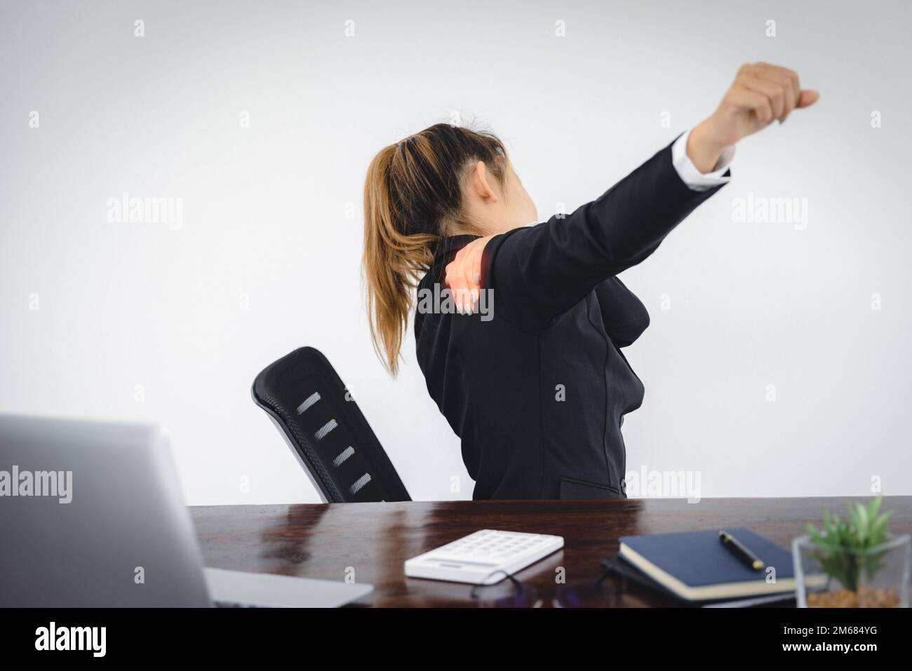 Femme d'affaires souffrant de douleurs à l'épaule sur le lieu de travail. Banque D'Images