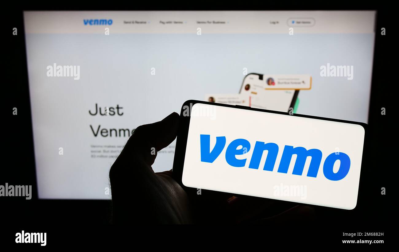 Personne tenant smartphone avec logo du service de paiement mobile Venmo sur l'écran devant le site Web. Mise au point sur l'affichage du téléphone. Banque D'Images