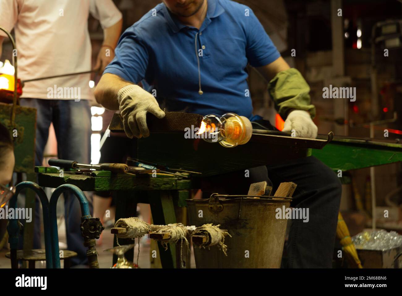 Un souffleur de verre travaille à la fabrication de vases et de verres en verre. Couper l'excédent de verre du produit jusqu'à 20 travailleurs peuvent être impliqués simul Banque D'Images