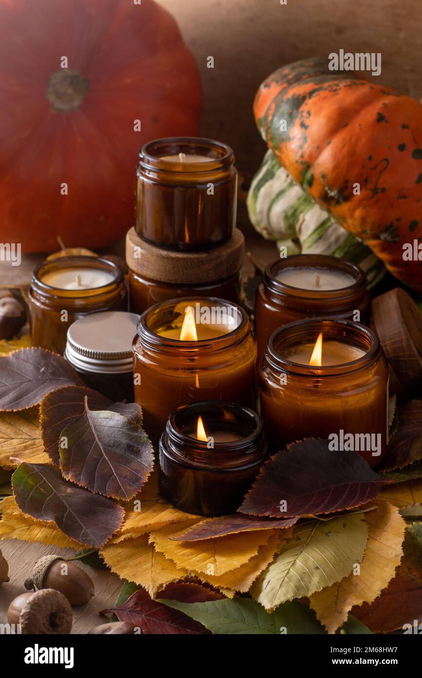 Les bougies de soja brûlent dans des pots en verre. Feuilles d'arbre, citrouille. Confort à la maison. Bougie dans un pot brun. Parfum et lumière. Bougie parfumée faite à la main. Aromathérapie. Ambiance d'automne. Décoration chaleureuse à l'automne. Banque D'Images