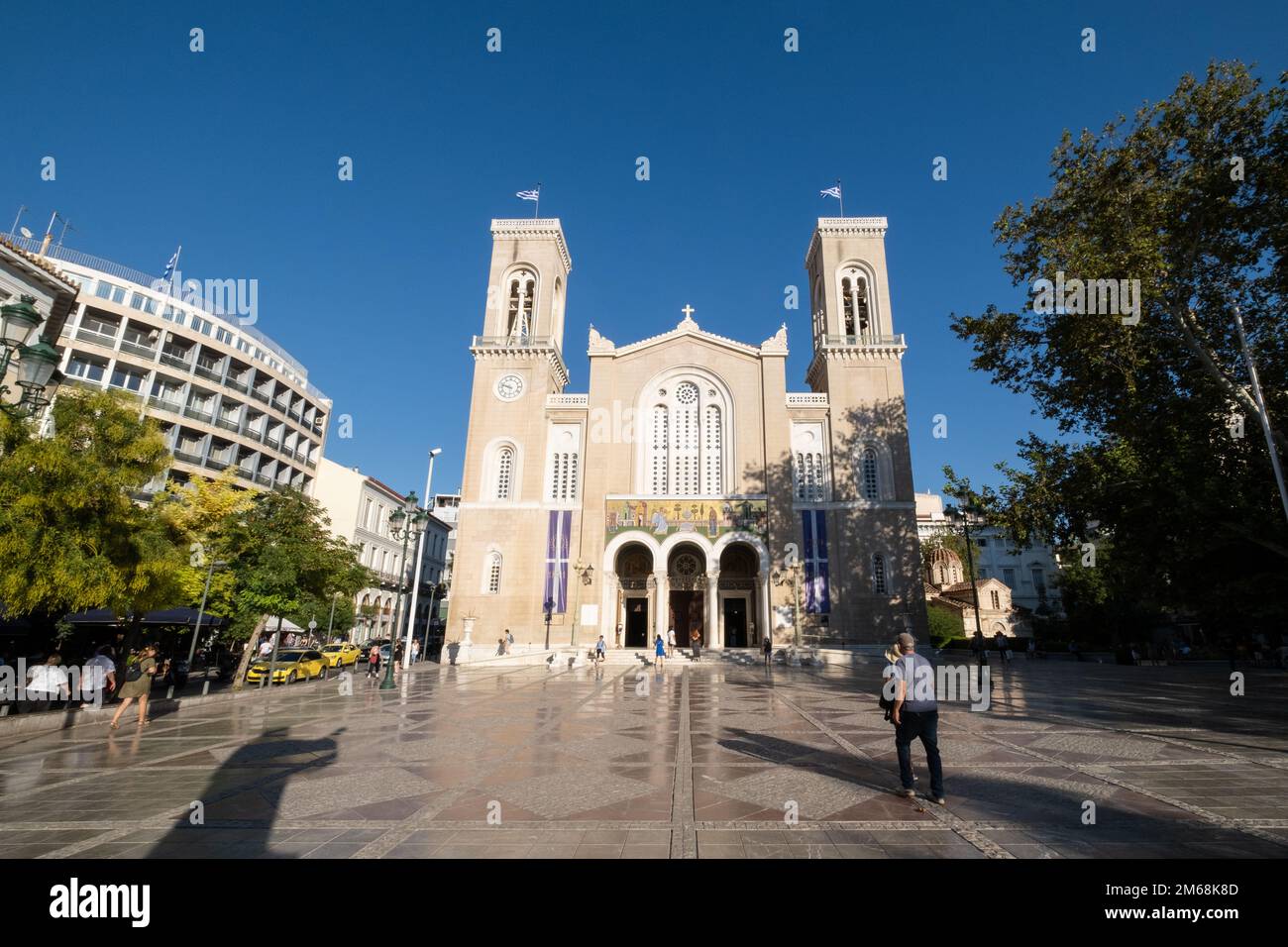 Cathédrale métropolitaine d'Athènes, Athènes, Grèce, un jour lumineux avec un ciel bleu profond au-dessus et quelques personnes marchant devant. L'ombre de la statue Banque D'Images