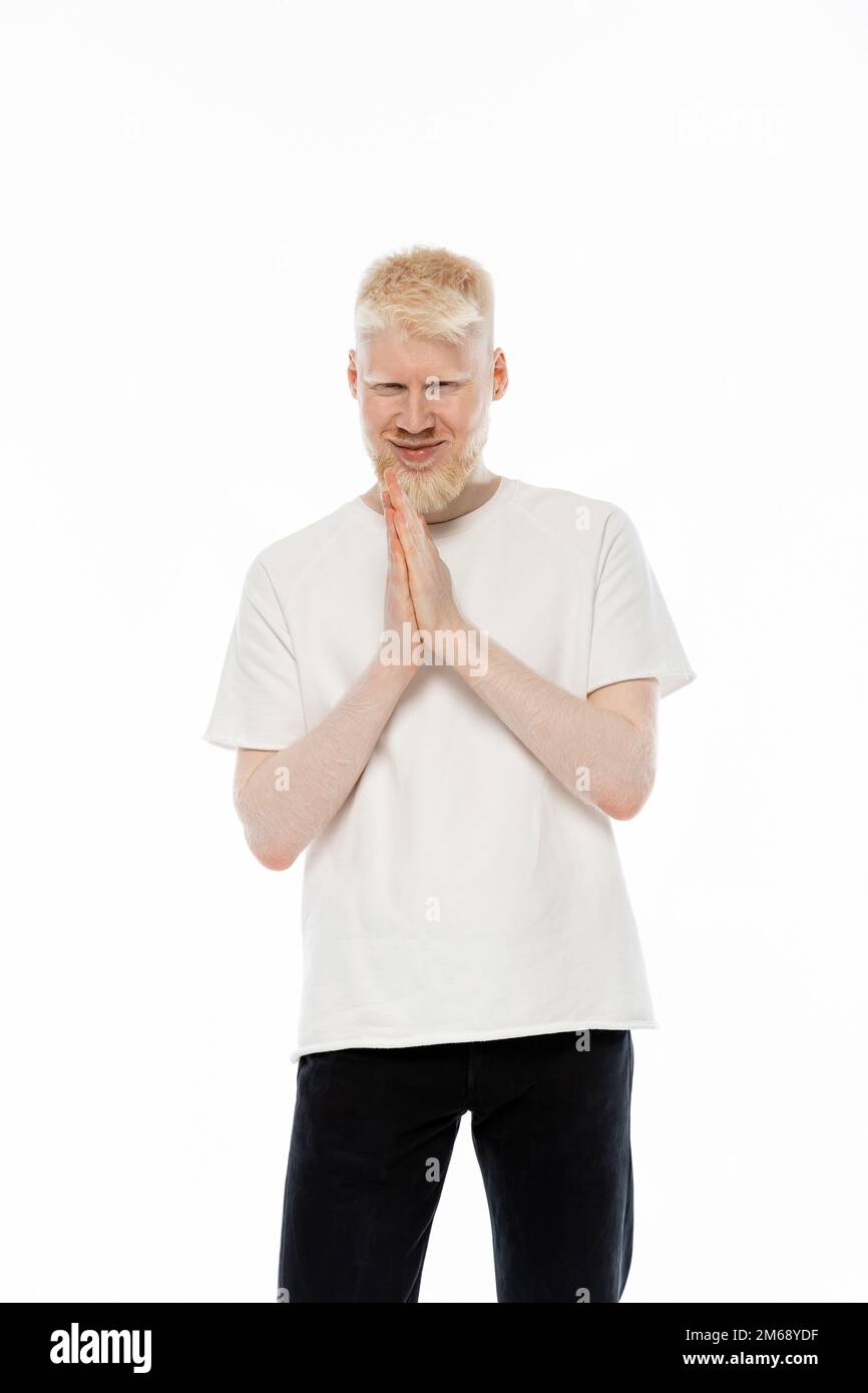homme albino gai en t-shirt debout avec des mains de prière isolées sur blanc, image de stock Banque D'Images