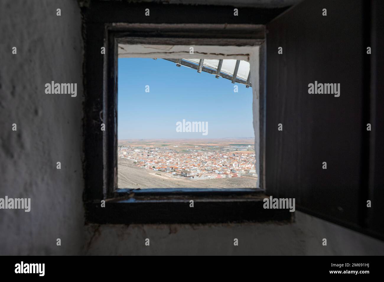 Fenêtre carrée d'un moulin à vent avec lames et vue sur la ville de Consuegra sur la route Don Quichotte en Espagne Banque D'Images