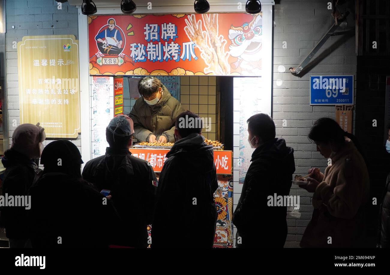 Jinan, province chinoise de Shandong. 2nd janvier 2023. Les gens se dressent devant un stand de nourriture sur Fukong Street à Jinan, dans la province de Shandong, en Chine orientale, le 2 janvier 2023. Furong Street, une vieille rue de 500 mètres de long avec plus de 150 boutiques de nourriture et de boissons, revient à son agitation de nos jours. Credit: Xu Suhui/Xinhua/Alamy Live News Banque D'Images