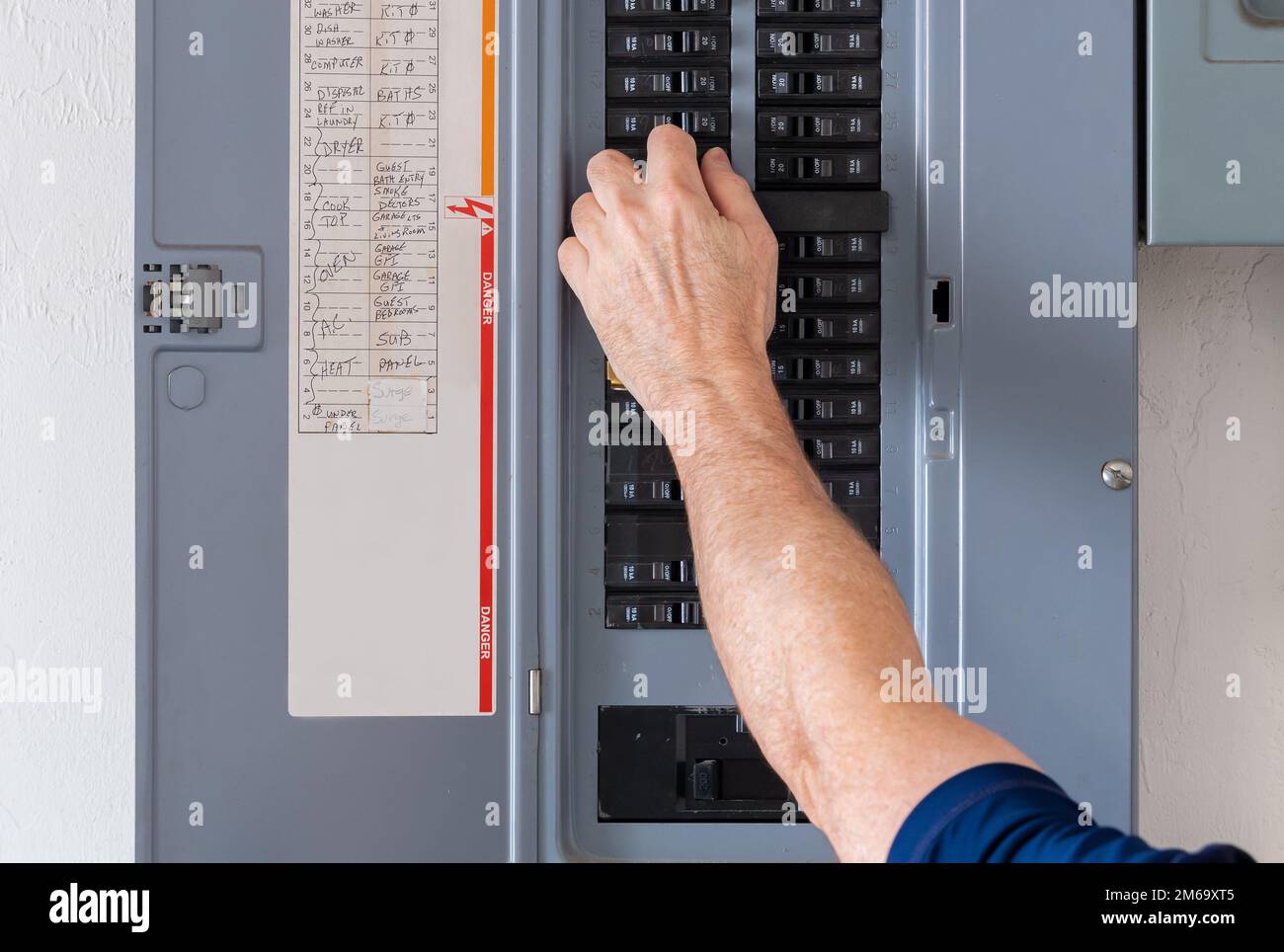 Réinitialisation du disjoncteur déclenché dans le panneau d'alimentation électrique résidentiel. Un électricien mâle coupe l'alimentation de la prise électrique au niveau du boîtier de disjoncteurs. Banque D'Images