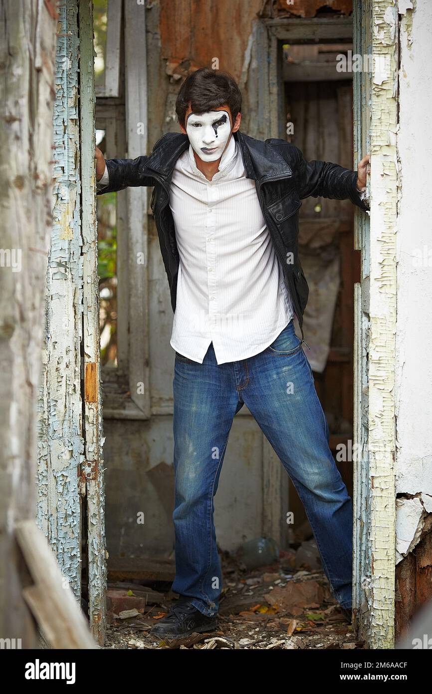 Guy mime contre la vieille porte en bois. Banque D'Images