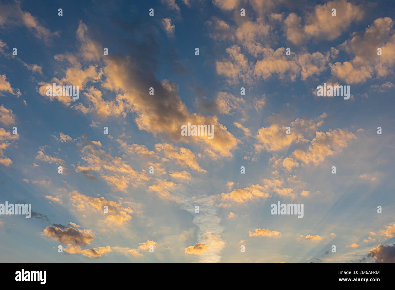 Des poutres de soleil éclaissent des nuages moelleux contre un ciel bleu de cobalt au crépuscule en Géorgie. Banque D'Images