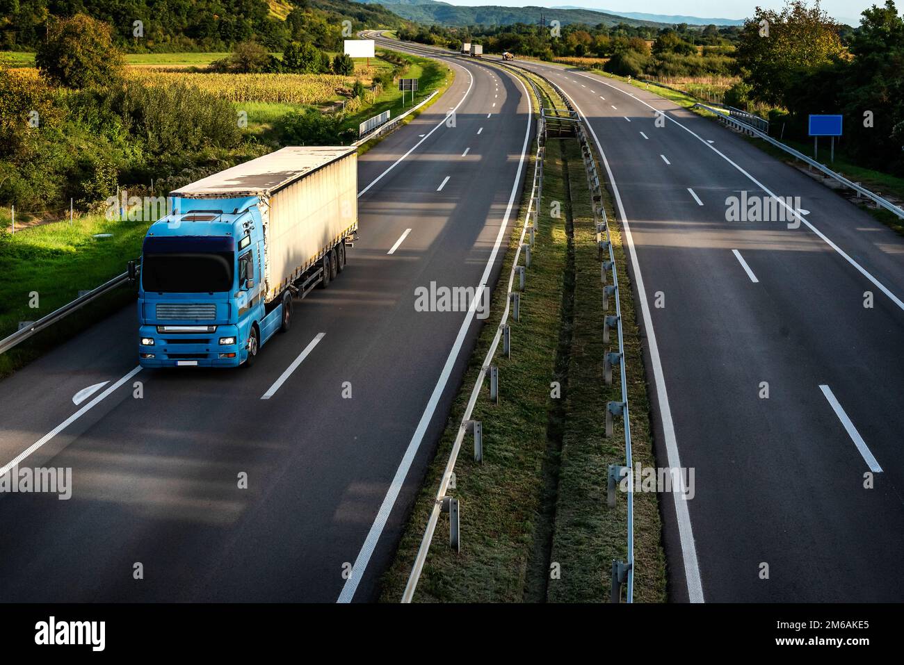 Grand semi-camion industriel bleu pour livraison de fret commercial long-courrier avec semi-remorque avançant le long de la route Banque D'Images