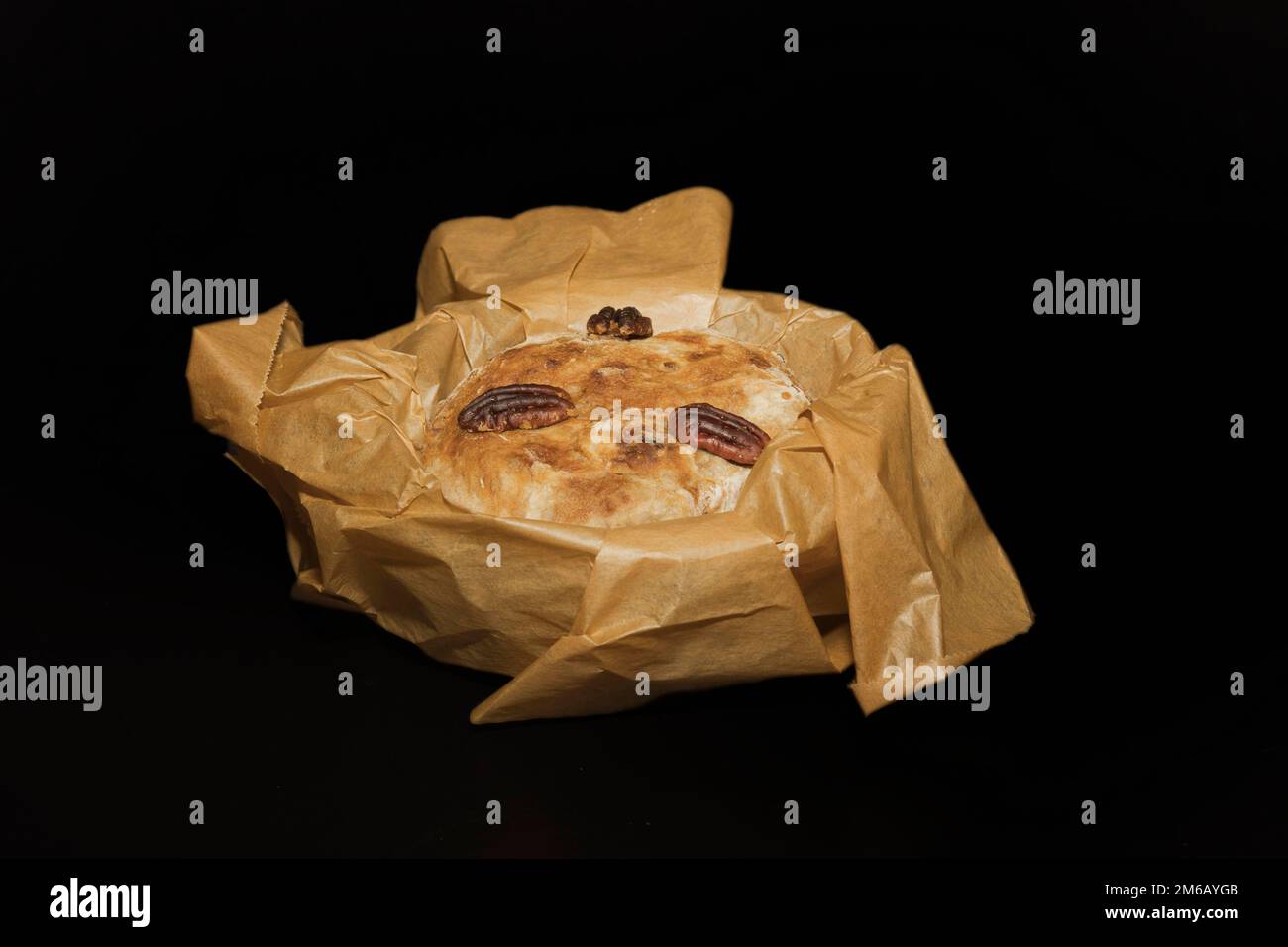 Pâte de levure aux pacanes (Carya illinoinensis) encore en papier de cuisson, photographie alimentaire avec fond noir Banque D'Images