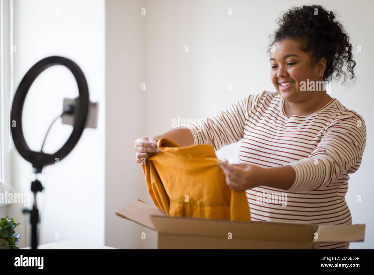 Femme émotive de surpoids de la mode blogger montrant des vêtements de marque, déballage de colis Banque D'Images