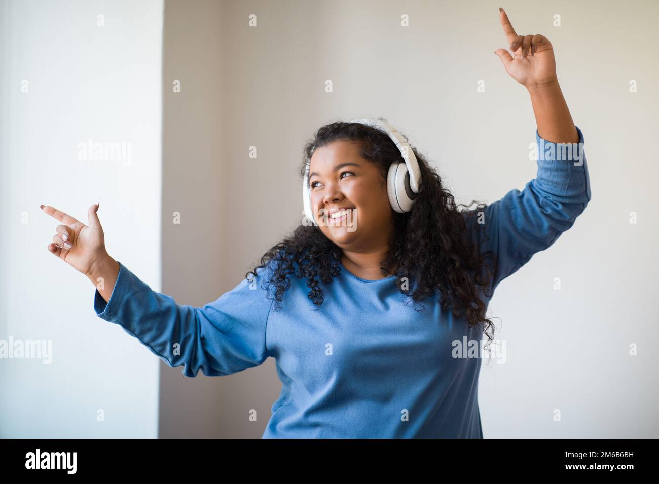 Belle femme de chubby positive dansant tout en s'amusant à la maison Banque D'Images