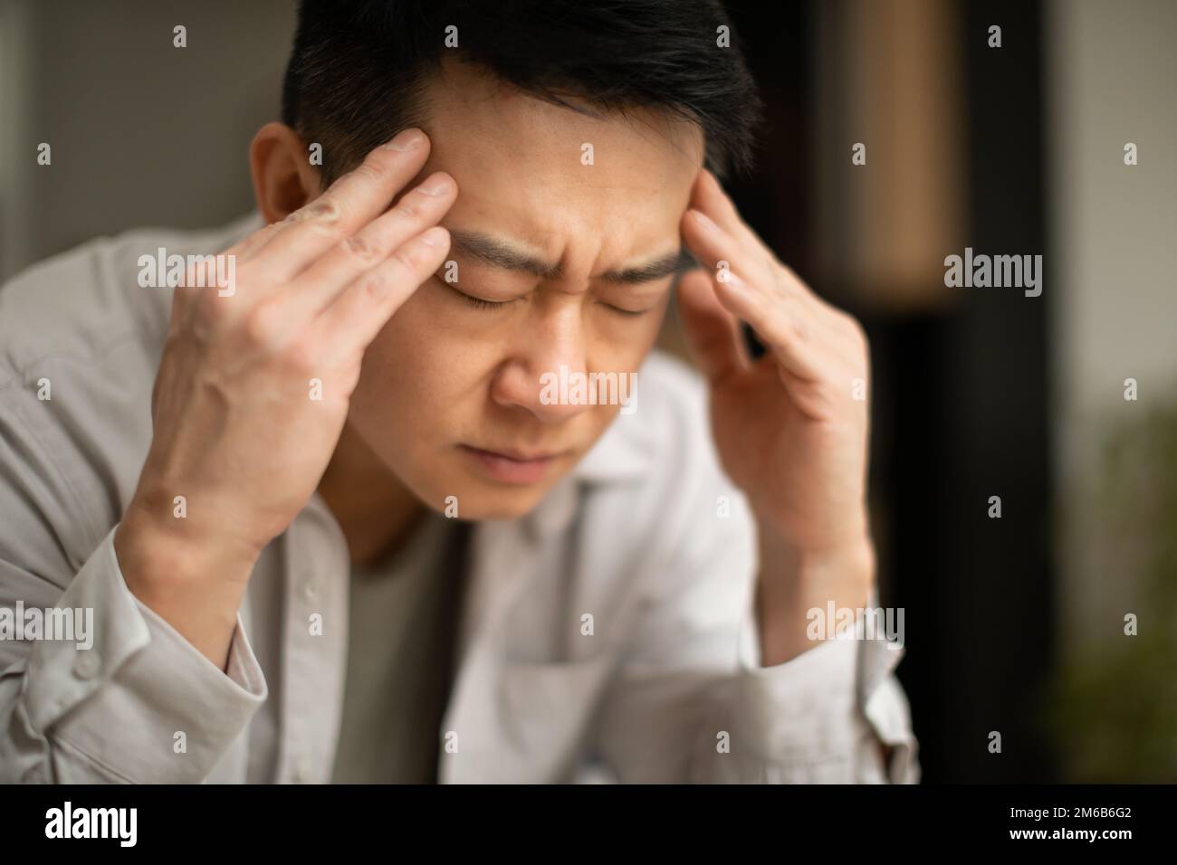 Gros plan d'un homme asiatique d'âge moyen souffrant de maux de tête, touchant ses temples, assis avec les yeux fermés, espace de copie Banque D'Images