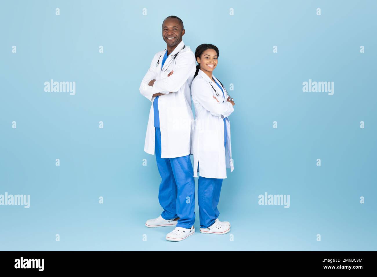 Homme de doc afro-américain mature et femme posant avec les bras pliés, médecins expérimentés portant des manteaux de laboratoire Banque D'Images
