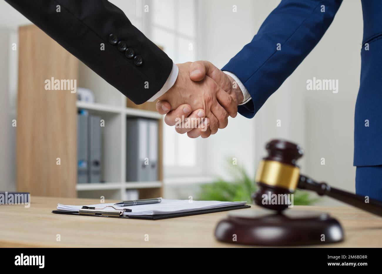 Un avocat professionnel échange des poignées de main avec le client au-dessus de la table de bureau avec le gavel du juge Banque D'Images
