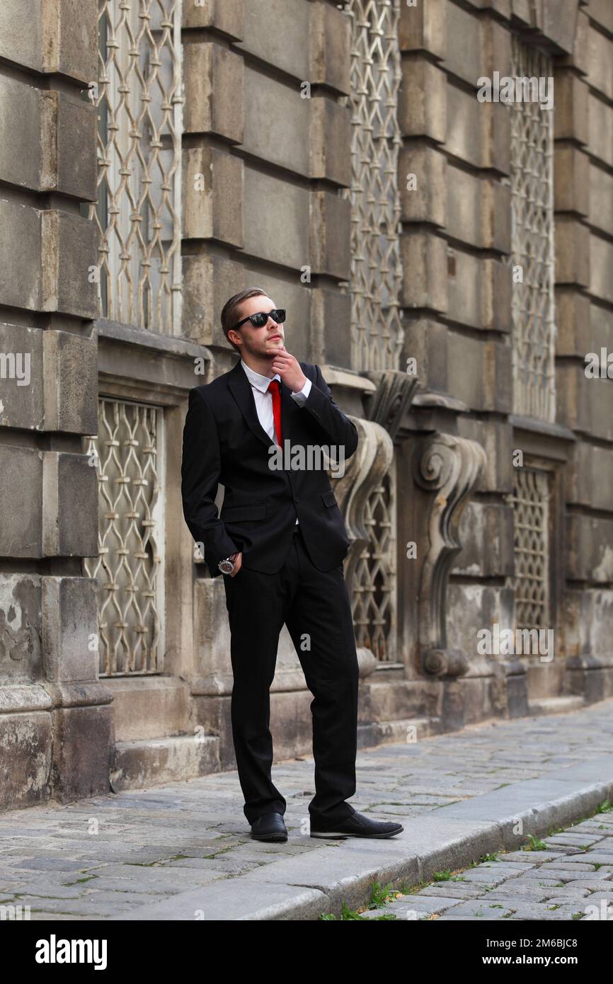 Jeune homme beau en costume noir avec cravate rouge dans la rue Photo Stock  - Alamy