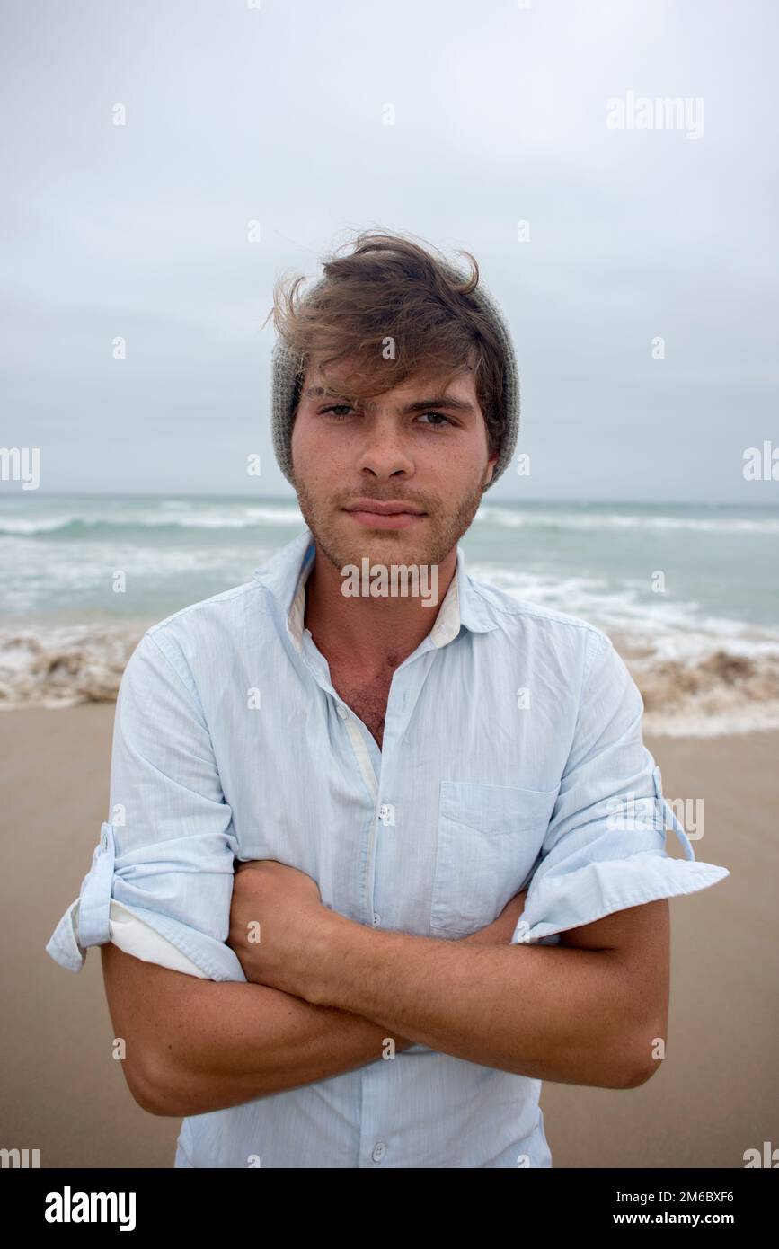 Jeune homme sur la plage avec les bras pliés Banque D'Images