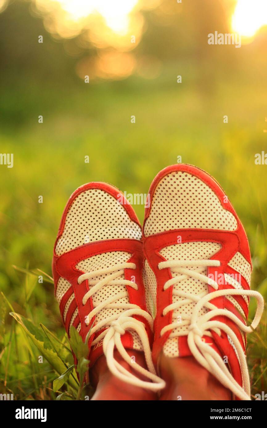 La détente. jeunes sneakers girl jambes sur herbe, journée ensoleillée, instagram look. Banque D'Images
