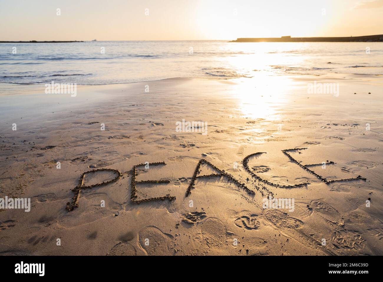 « Paix » écrit sur le sable à la plage au coucher du soleil, photo avec espace de copie Banque D'Images