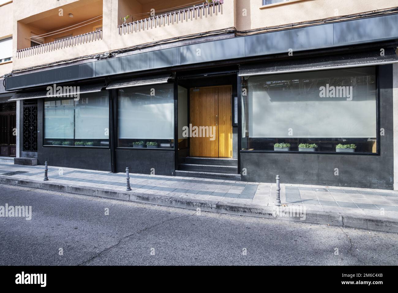 Façade d'un bâtiment avec un magasin au niveau de la rue avec entrée en bois avec escaliers, fenêtres peintes en noir et gris Banque D'Images