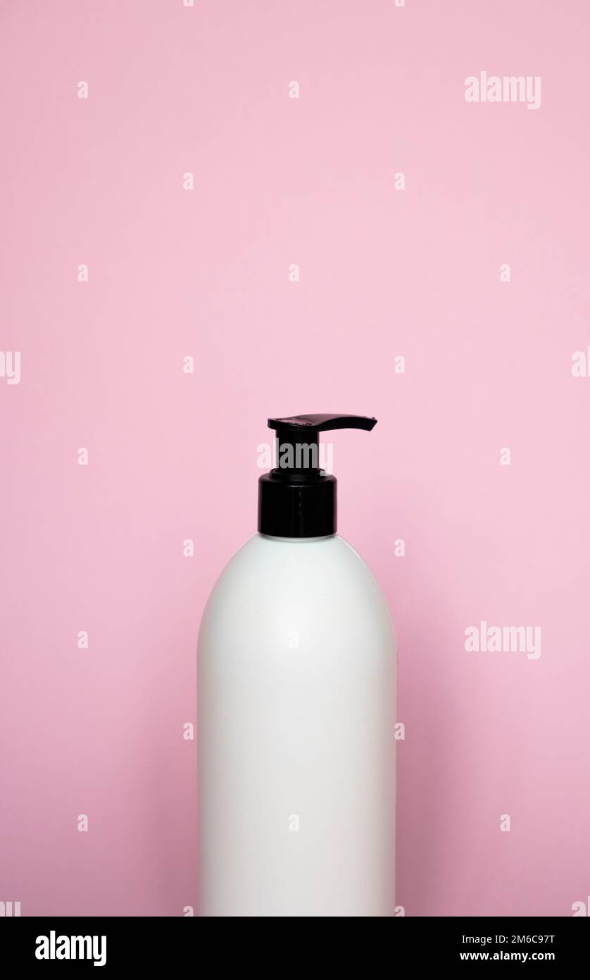 Flacon blanc avec distributeur noir pour savon liquide, shampooing, gel sur fond rose. Banque D'Images