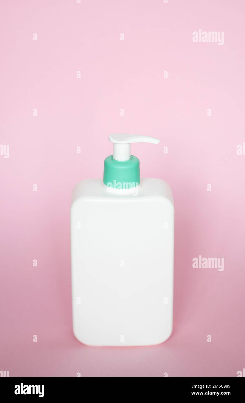 Flacon carré blanc avec distributeur cyan pour savon liquide, shampooing, gel sur fond rose. Banque D'Images