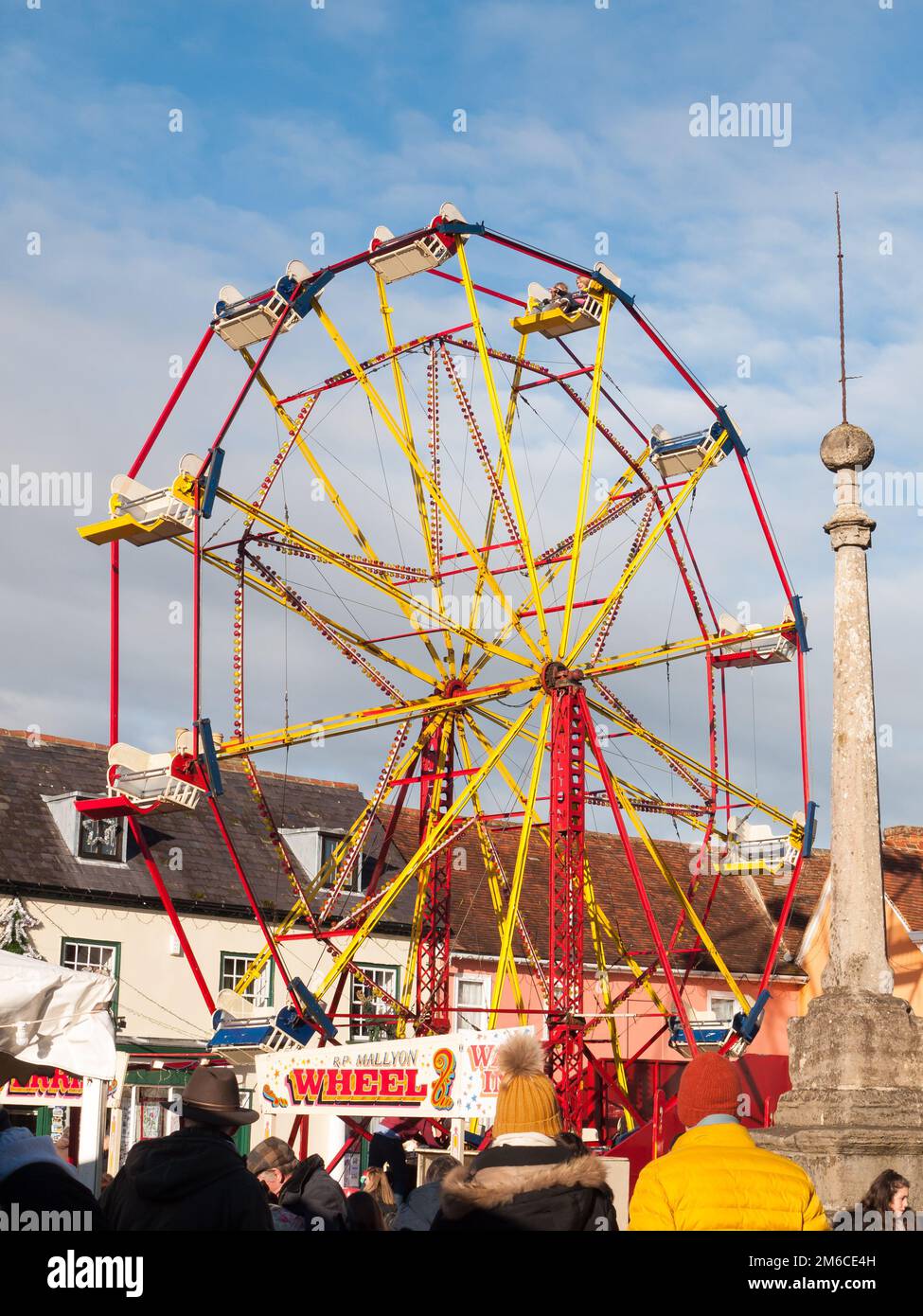 Roue de carrousel rouge et jaune à l'extérieur avec des personnes au-dessous du ciel bleu salon de noël Banque D'Images