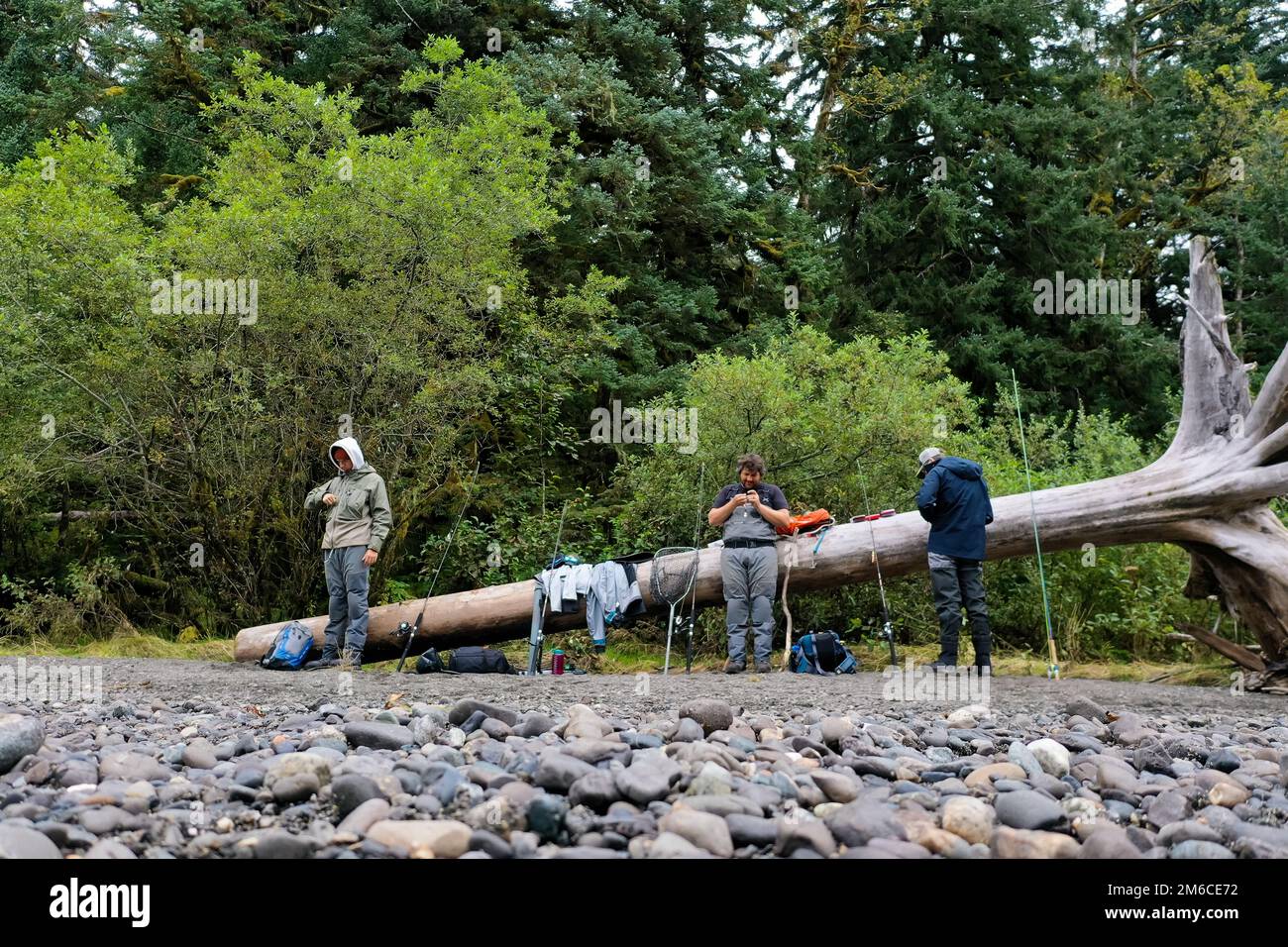 Les pêcheurs de la rivière reposent sur une bûche au bord de la forêt verte Banque D'Images