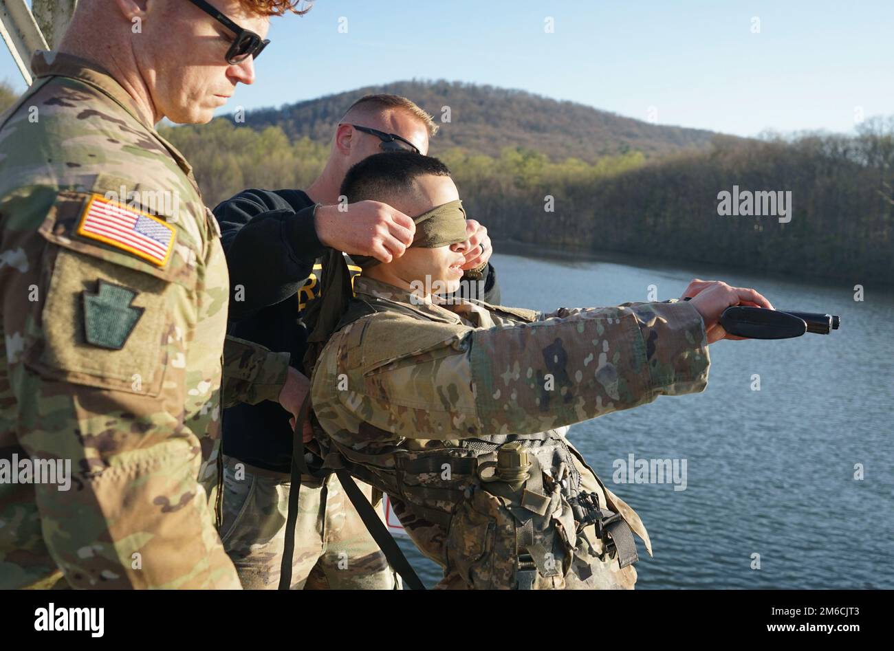 Sgt. 1st classe Erich Friedlein, officier non commandant en charge du Programme d'évaluation des Rangers et des Sapper de la Garde nationale de Pennsylvanie, aveugle un membre de service pendant la partie du test de survie en eau de combat du RER sur 22 avril 2022 à fort Indiantown Gap, Pennsylvanie. Les membres du service ont été confrontés au défi de porter un porte-charge de combat, de porter une arme en caoutchouc et de se replier les yeux bandés, lorsqu'ils ont sauté d'un quai et ont dû nager jusqu'à la rive Banque D'Images