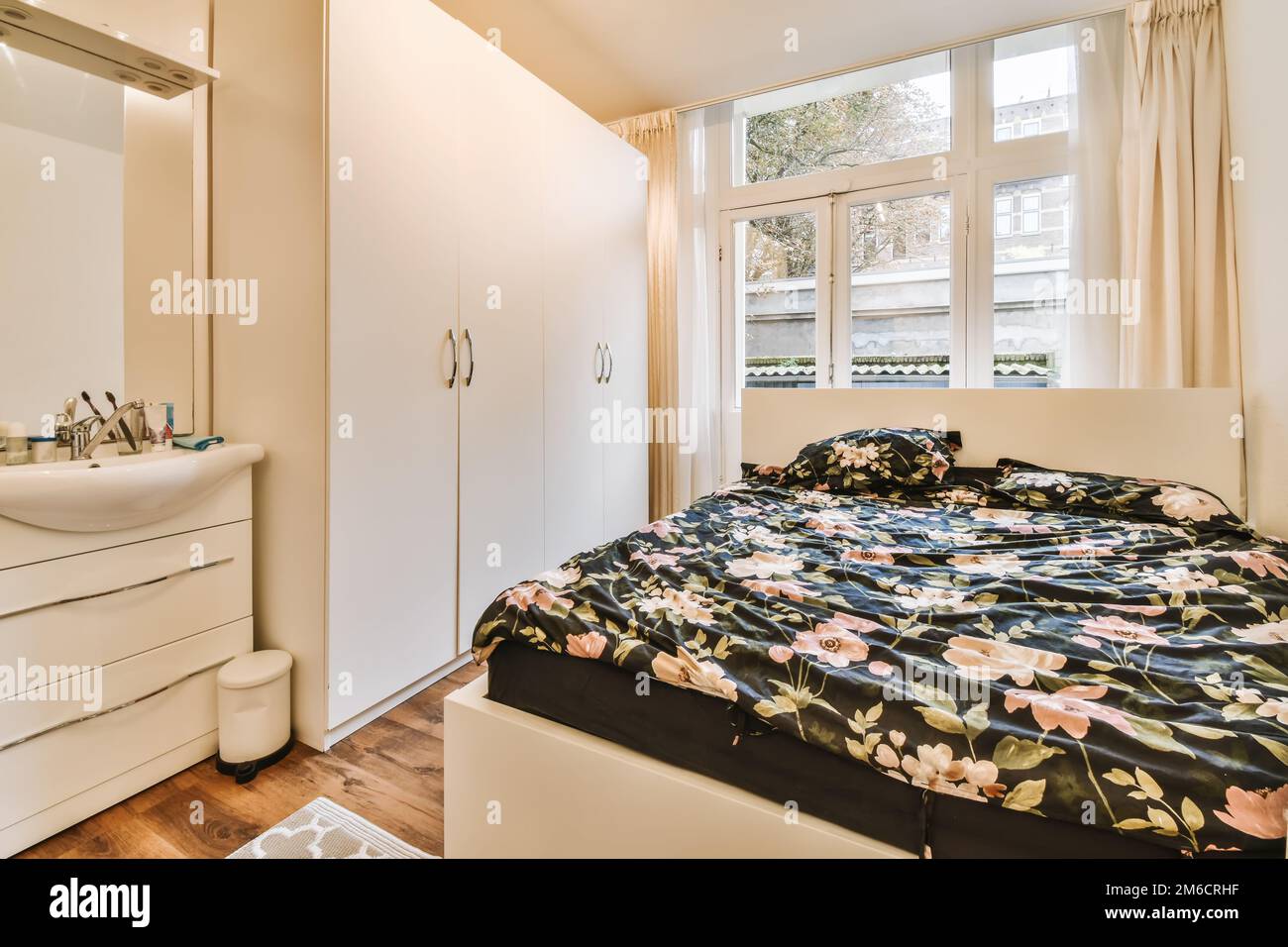 une chambre avec un lit, une commode et un miroir sur le mur devant la porte de la salle de bains Banque D'Images