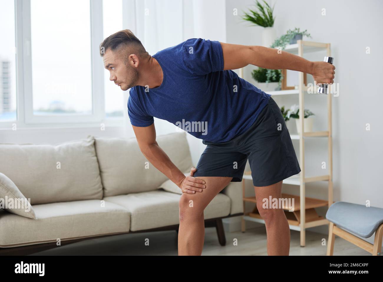 Homme sportif entraînement à la maison avec haltères, exercices pour les  bras et les muscles du dos, corps fort et posture correcte, le concept de  santé et de beauté Photo Stock -