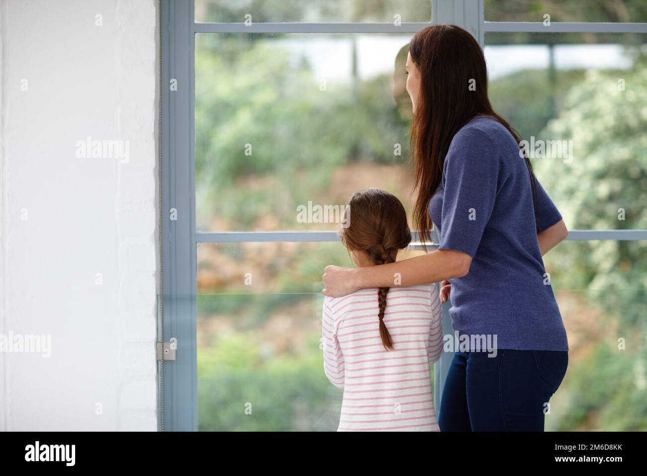 Moments spéciaux avec maman. Vue arrière d'une mère et d'une fille aimantes, en regardant par la fenêtre. Banque D'Images