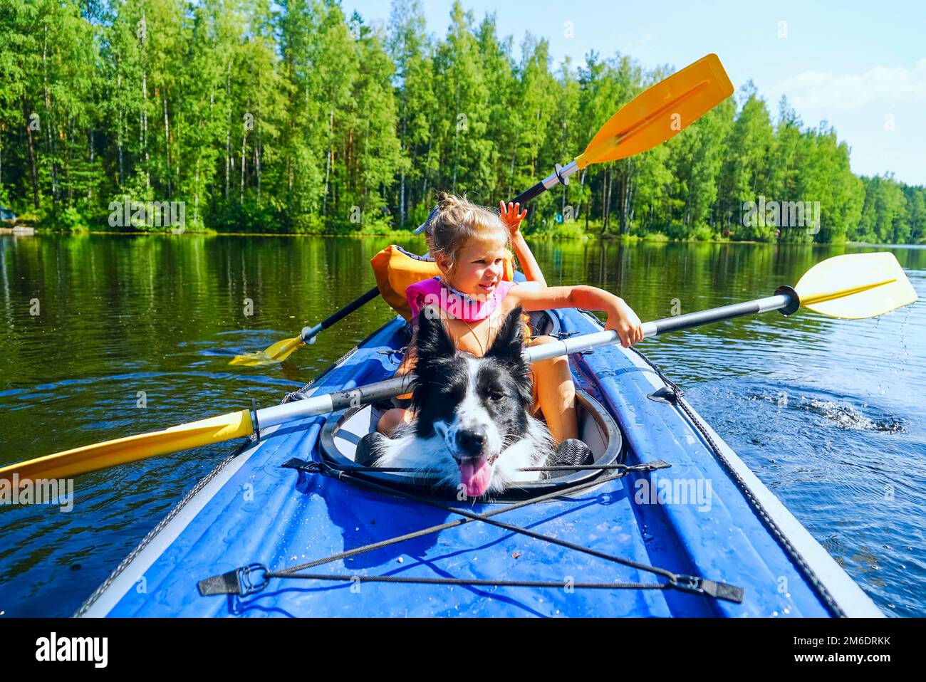 Une fille avec un chien assis dans un kayak sur le lac . Banque D'Images