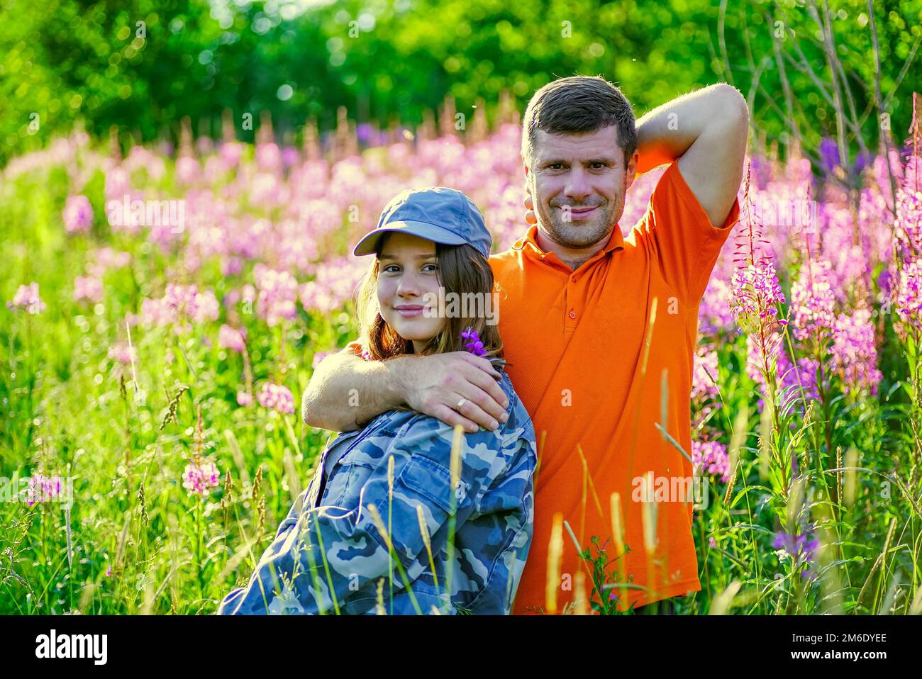 Une jeune fille et un homme s'embrassent dans l'herbe haute avec des fleurs . Banque D'Images