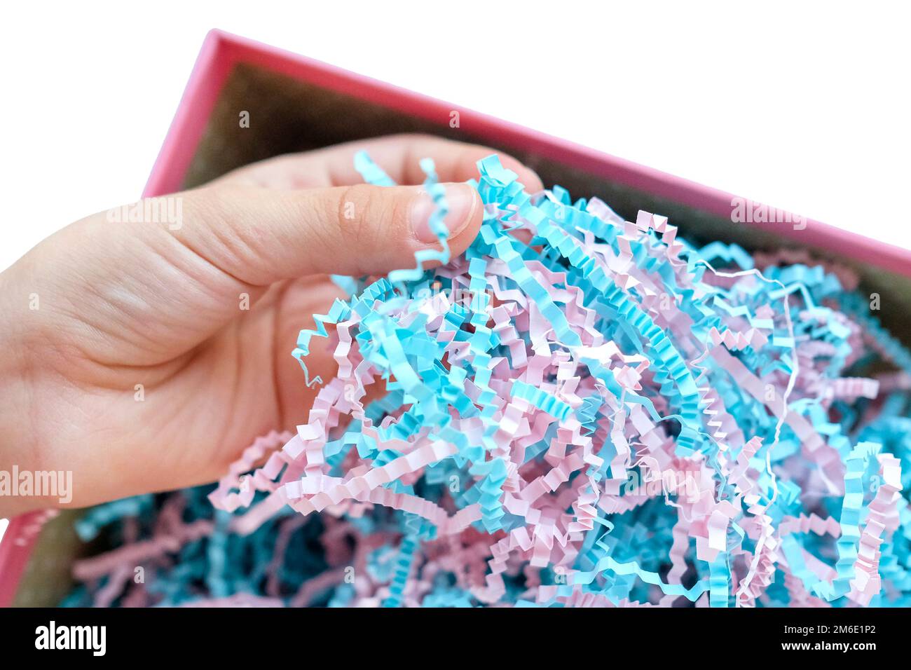 La main touche les copeaux de papier dans une boîte. Papier d'emballage fin Banque D'Images