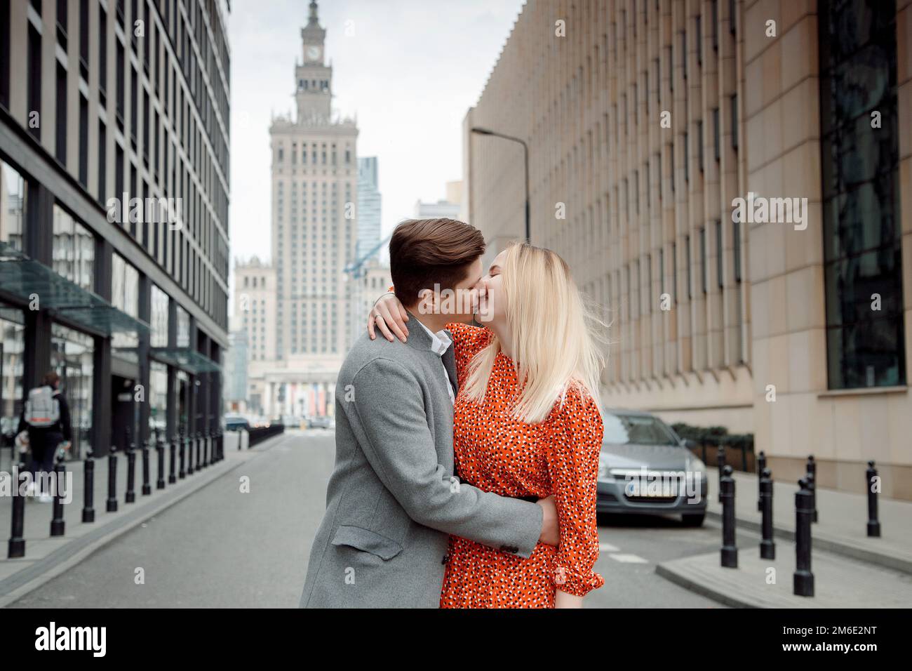 Couple touristique dans la grande ville. Le gars avec la fille est embrassant et heureux. Fille en robe rouge embrassant garçon. Banque D'Images