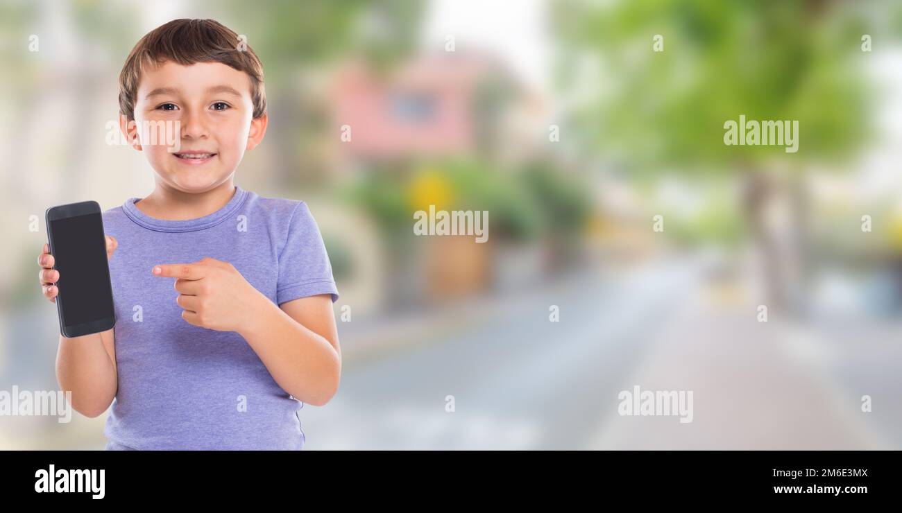Garçon enfant pointant vers smartphone smartphone smartphone téléphone portable bannière ville copyspace copier espace publicité Banque D'Images