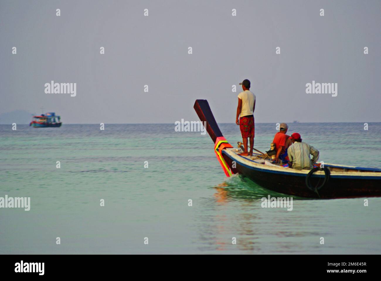 Trois hommes sur un bateau en bois avec ruban coloré observant la ligne horizontale sur la côte de l'île de Koh Lipe en Thaïlande, jour ensoleillé d'été Banque D'Images