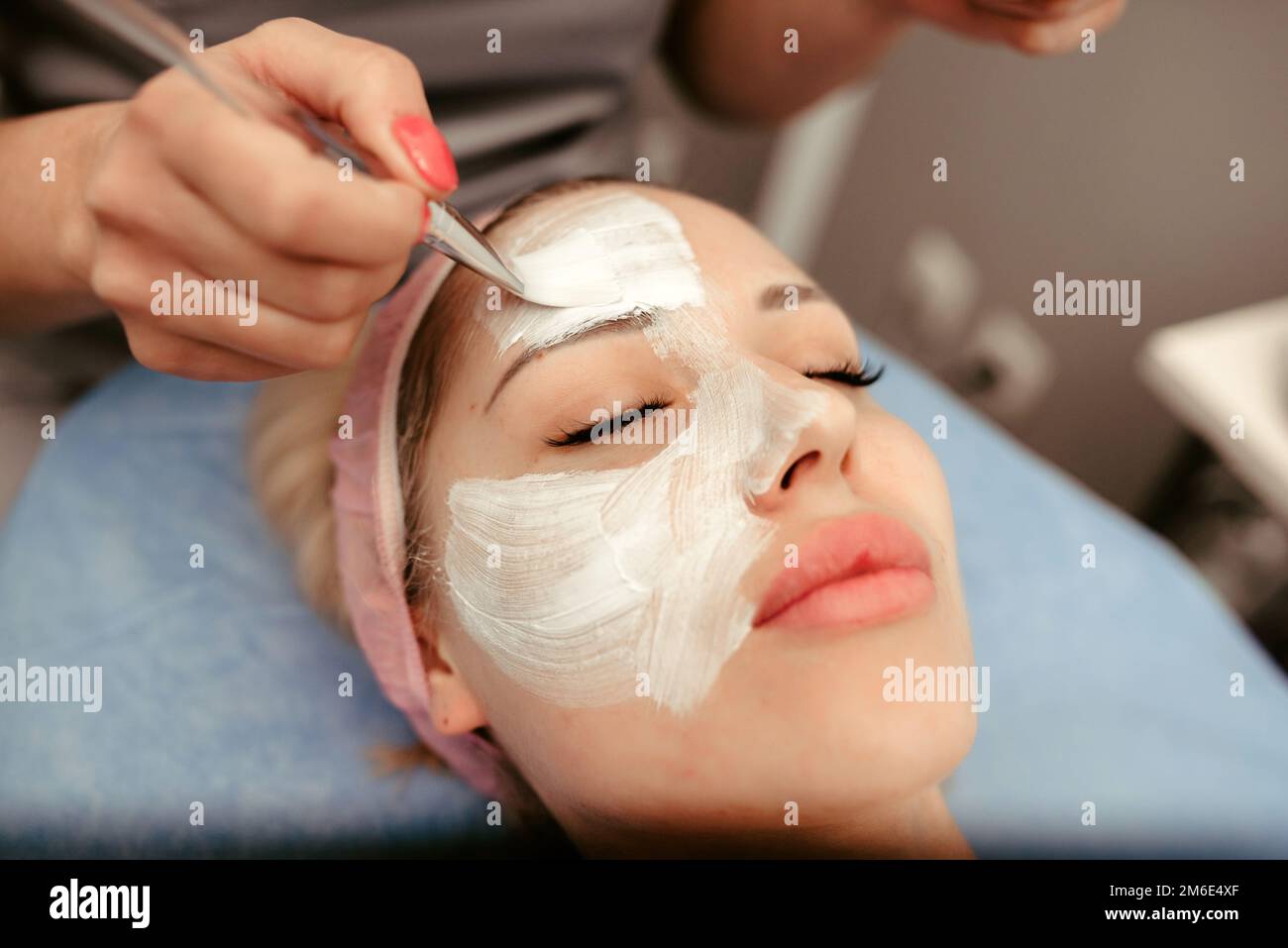 Belle jeune femme ayant un masque cosmétique facial au salon de spa Banque D'Images