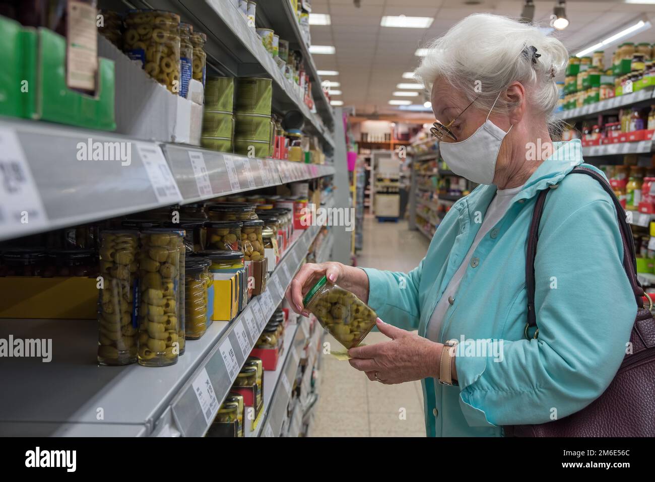 Femme âgée avec des magasins de masque dans le supermarché Banque D'Images