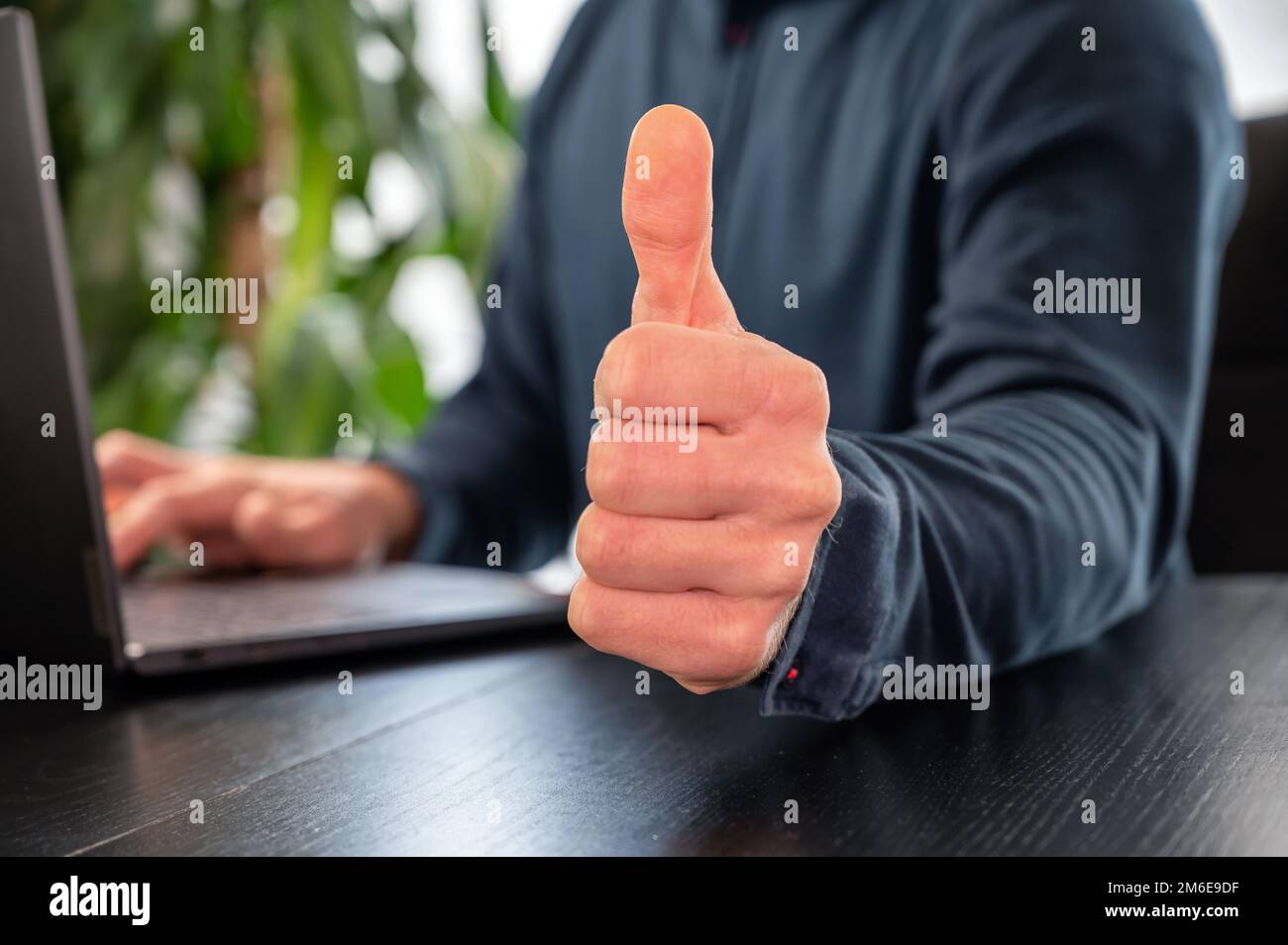 L'homme au bureau montre le geste du pouce vers le haut Banque D'Images