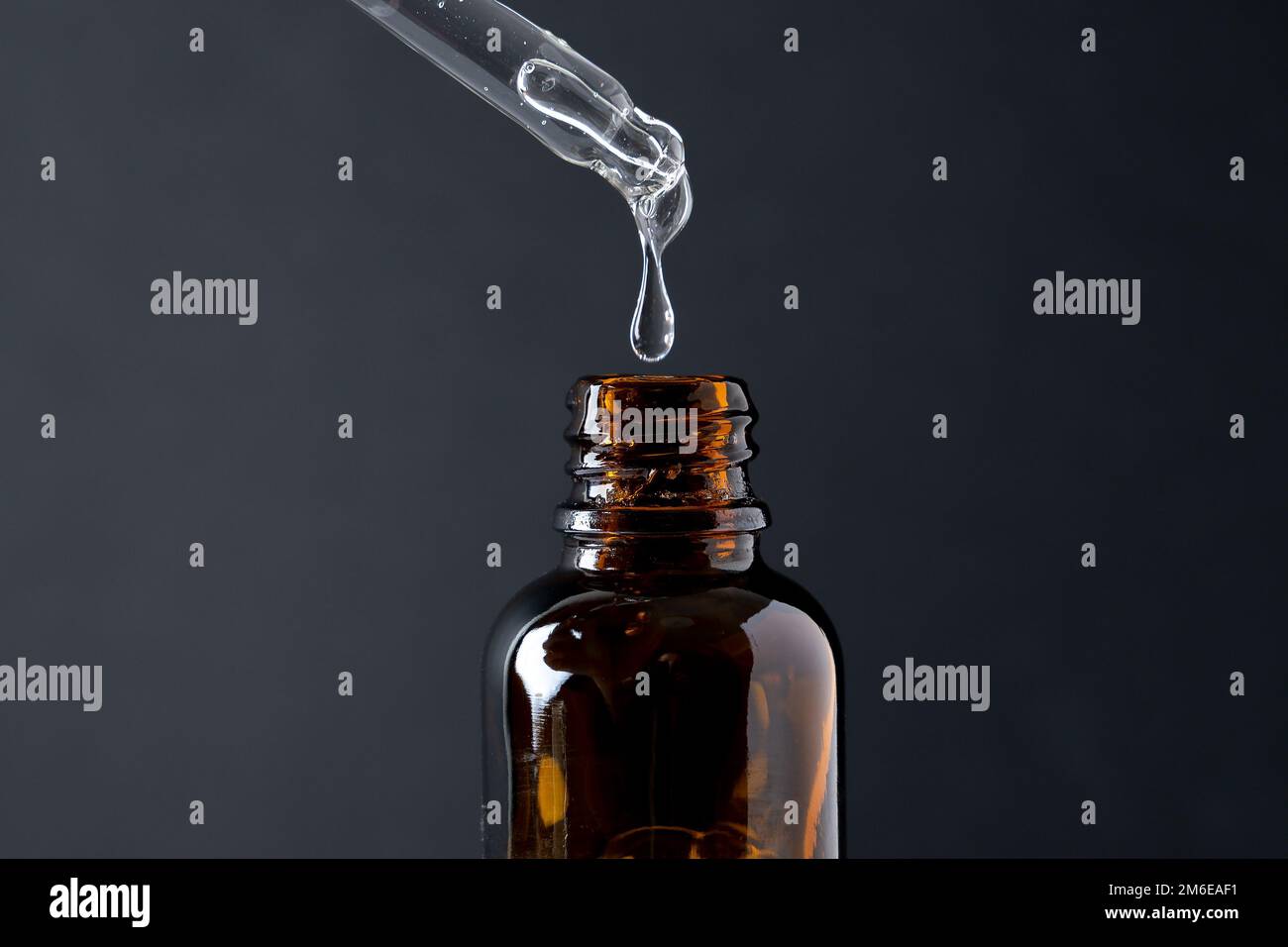 Pipeter avec du gel transparent liquide, du sérum ou de l'huile essentielle sur du noir. Avec flacon en verre Banque D'Images