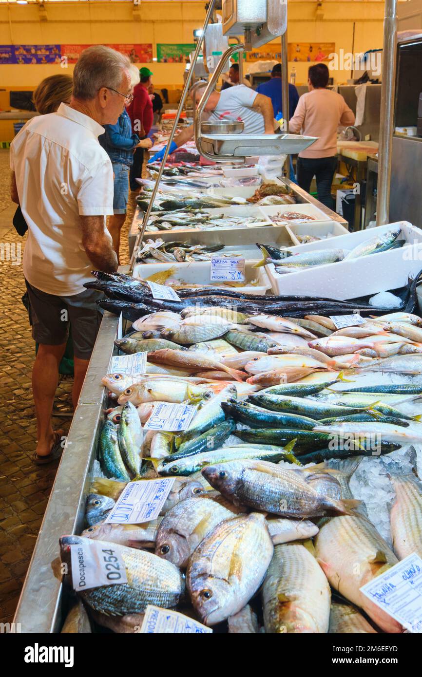 Clients regardant le poisson frais sur glace dans un restaurant local. Au marché de Tavira, Mercado à Tavira, Algarve, Portugal, Europe. Banque D'Images